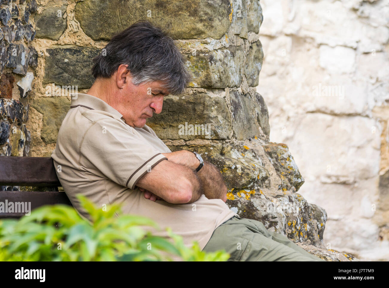Tired concept. Man sleeping on a bench outside in the Summer. Stock Photo