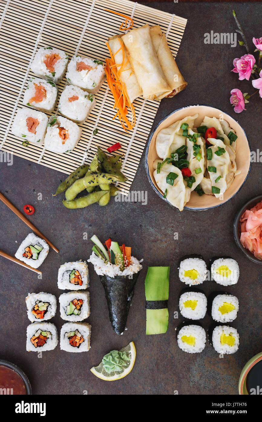 Various sushi, Japanese  lunch and side dishes and dipping sauces on dark background. Top view, blank space Stock Photo