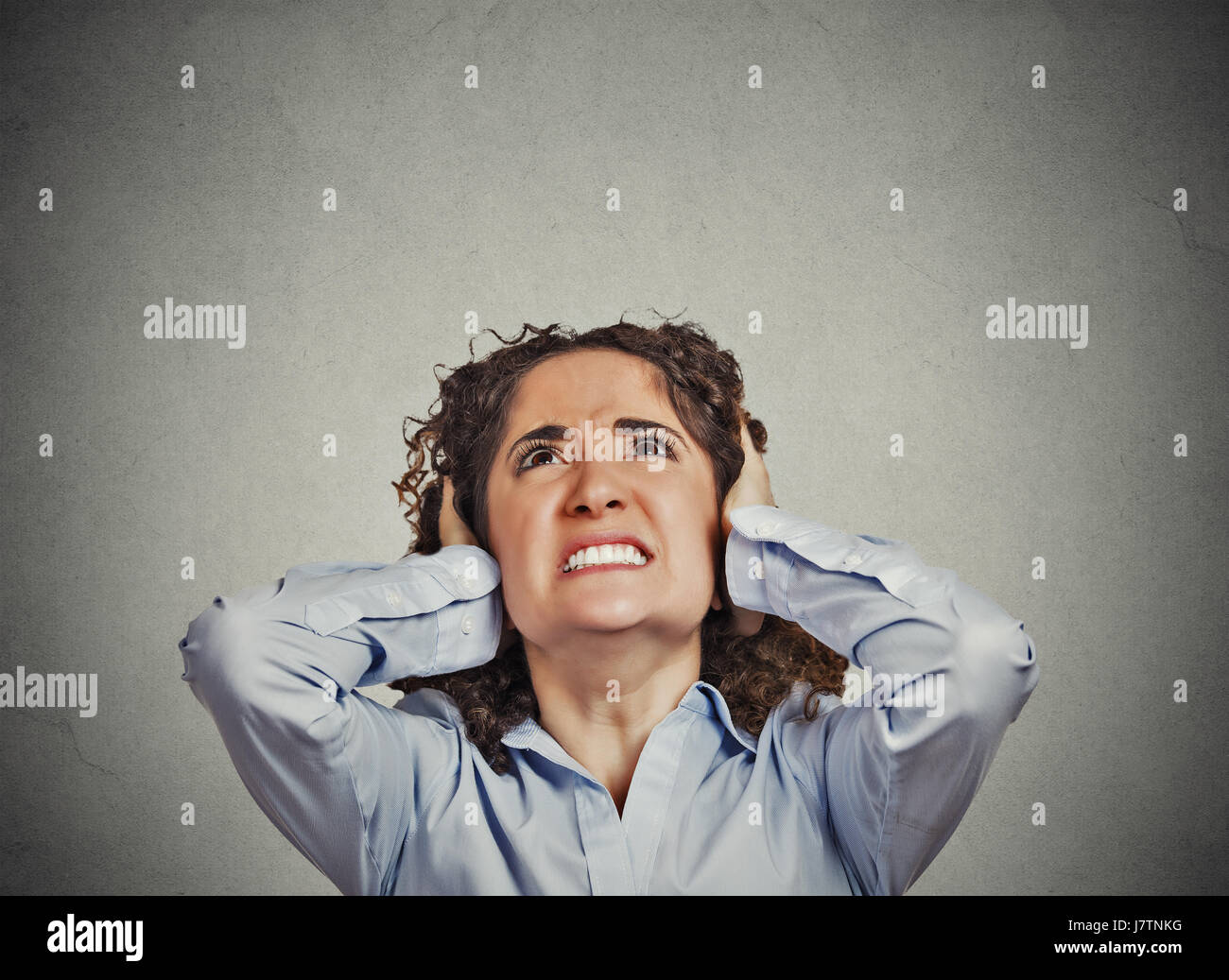 Closeup portrait young angry unhappy stressed woman covering her ears