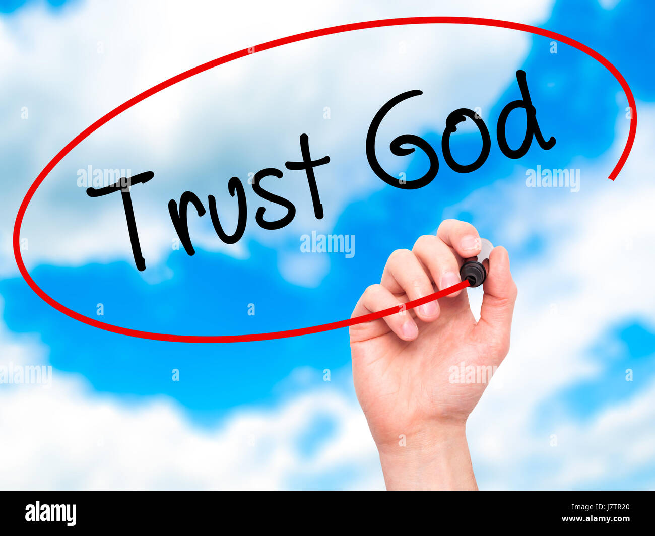 Man Hand writing Trust God  with black marker on visual screen. Isolated on sky. Business, technology, internet concept. Stock Photo Stock Photo
