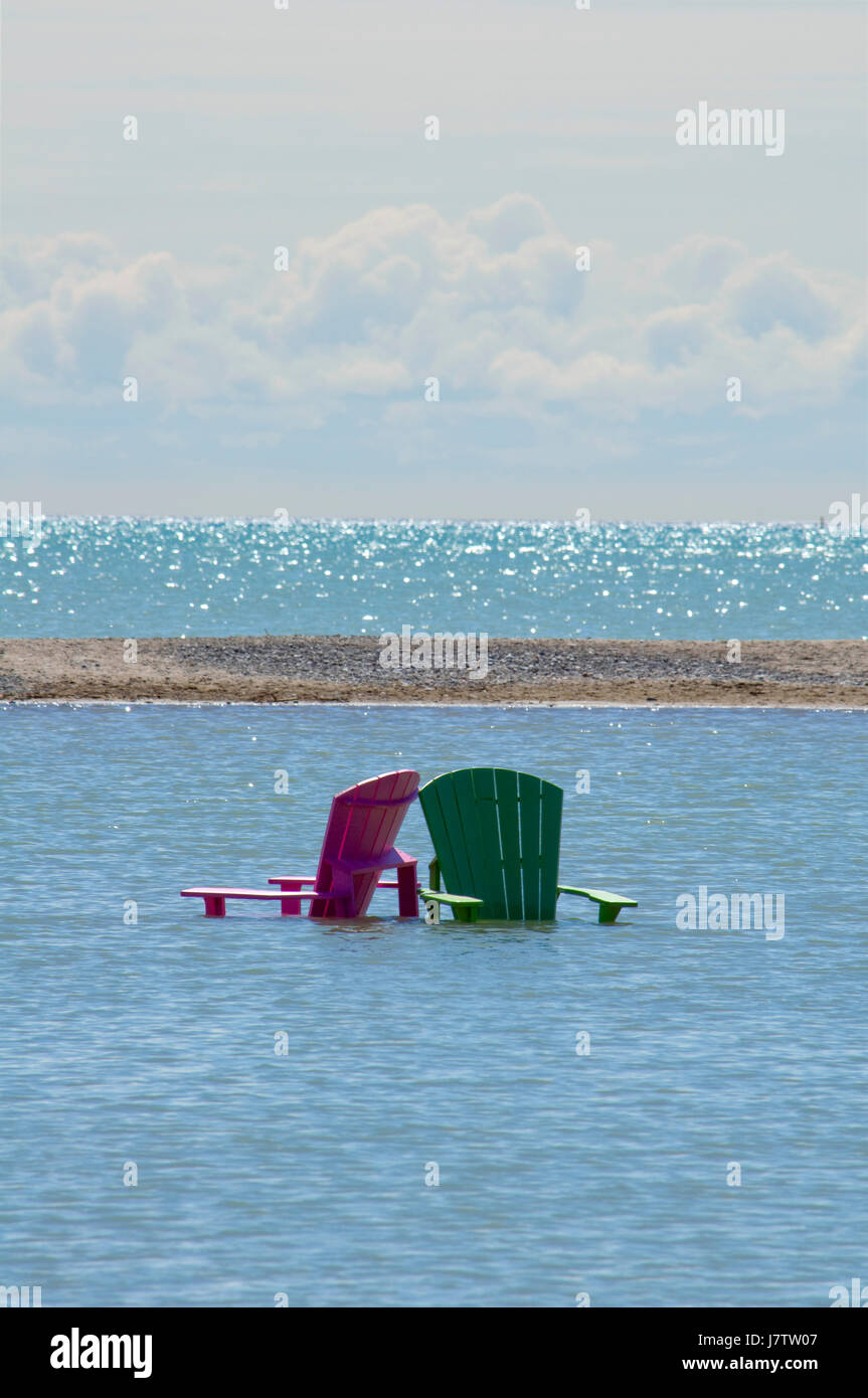 Muskoka chairs partially submerged in water and sand after springtime floods and high lake waters in Toronto, Ontario, Canada Stock Photo