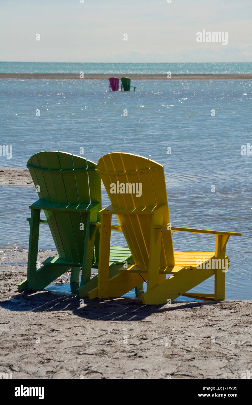 Muskoka Chairs Partially Submerged In Water And Sand After