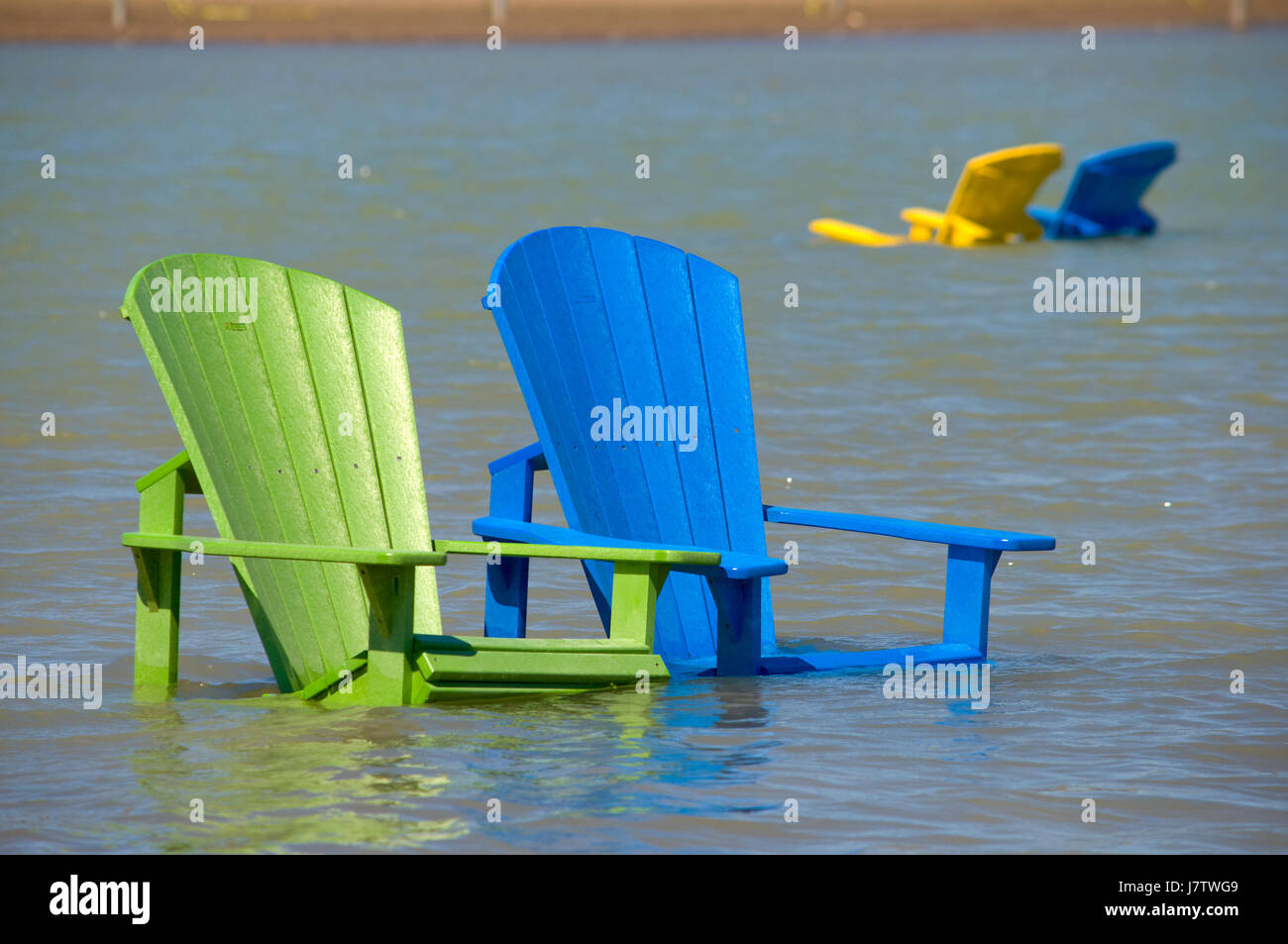 Muskoka chairs partially submerged in water and sand after springtime