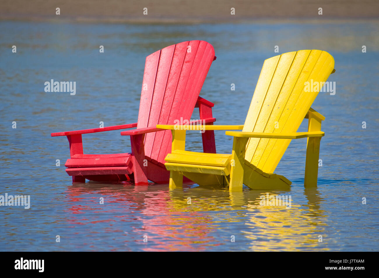 Muskoka chairs partially submerged in water and sand after springtime