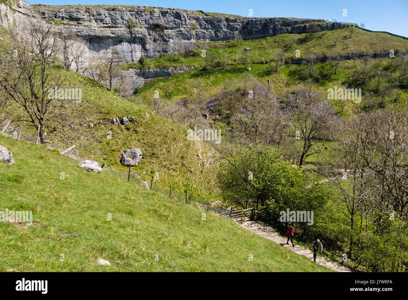 View of Malham Cove from Pennine Way path with people walking up. Malham, Malhamdale, Yorkshire Dales National Park, North Yorkshire, England, UK Stock Photo