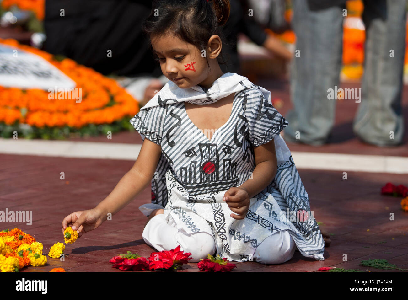A little girl holds flowers in hand to pay respect to language martyrs at the Central Shaheed Minar. Dhaka, Bangladesh. Stock Photo