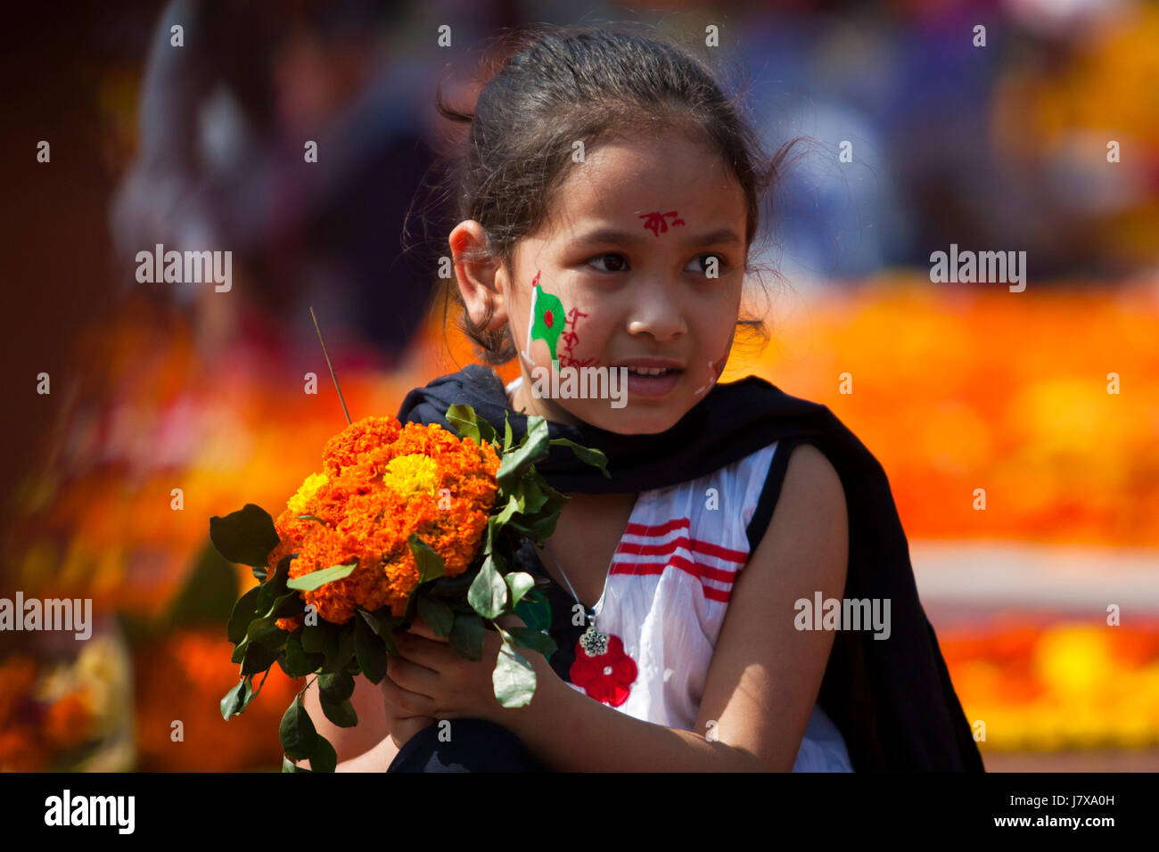 A little girl holds flowers in hand to pay respect to language martyrs ...