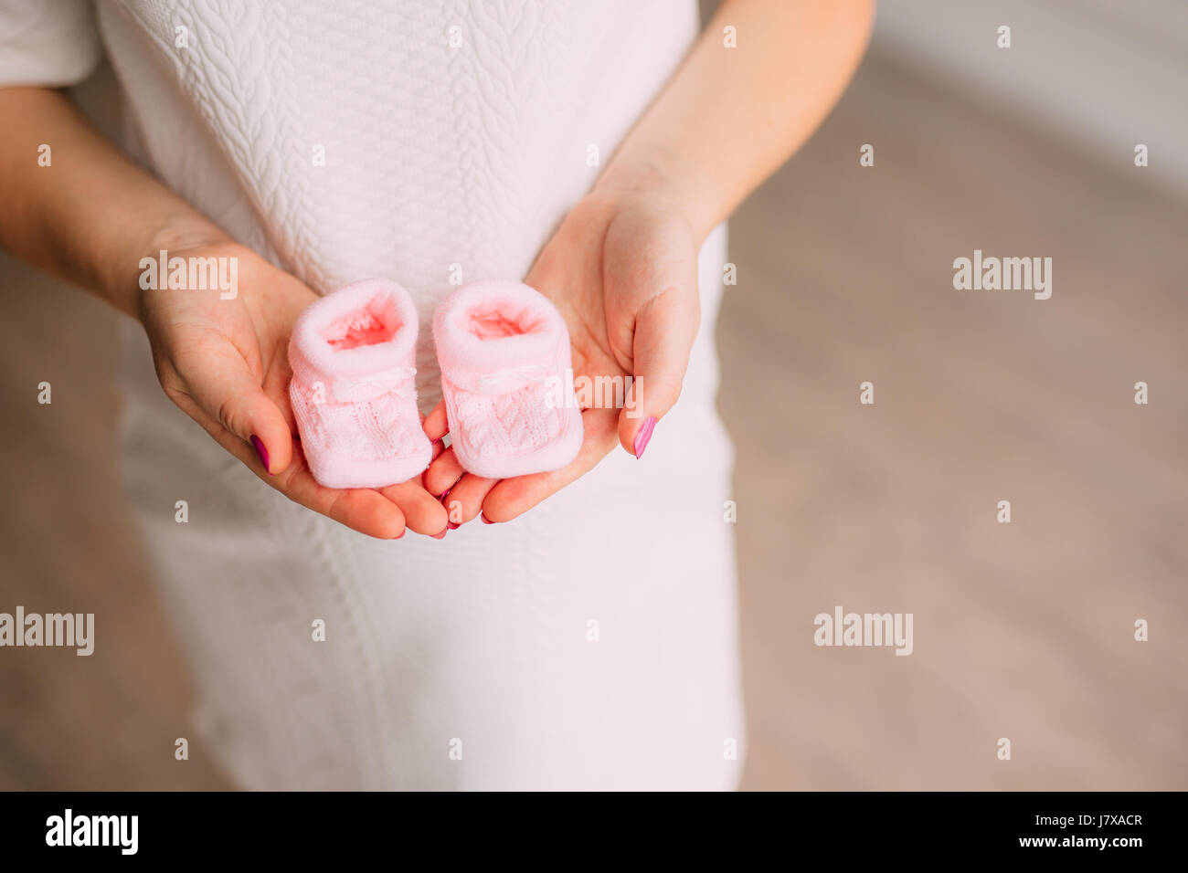 Baby booties in the hands of pregnant mother Stock Photo