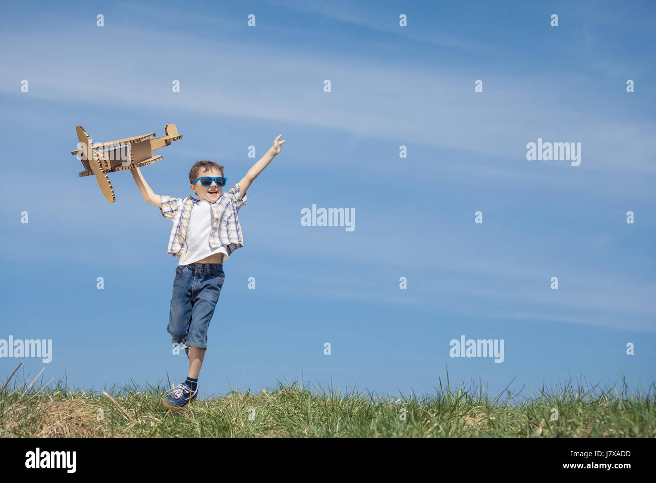 Little boy playing with cardboard toy airplane in the park at the day ...