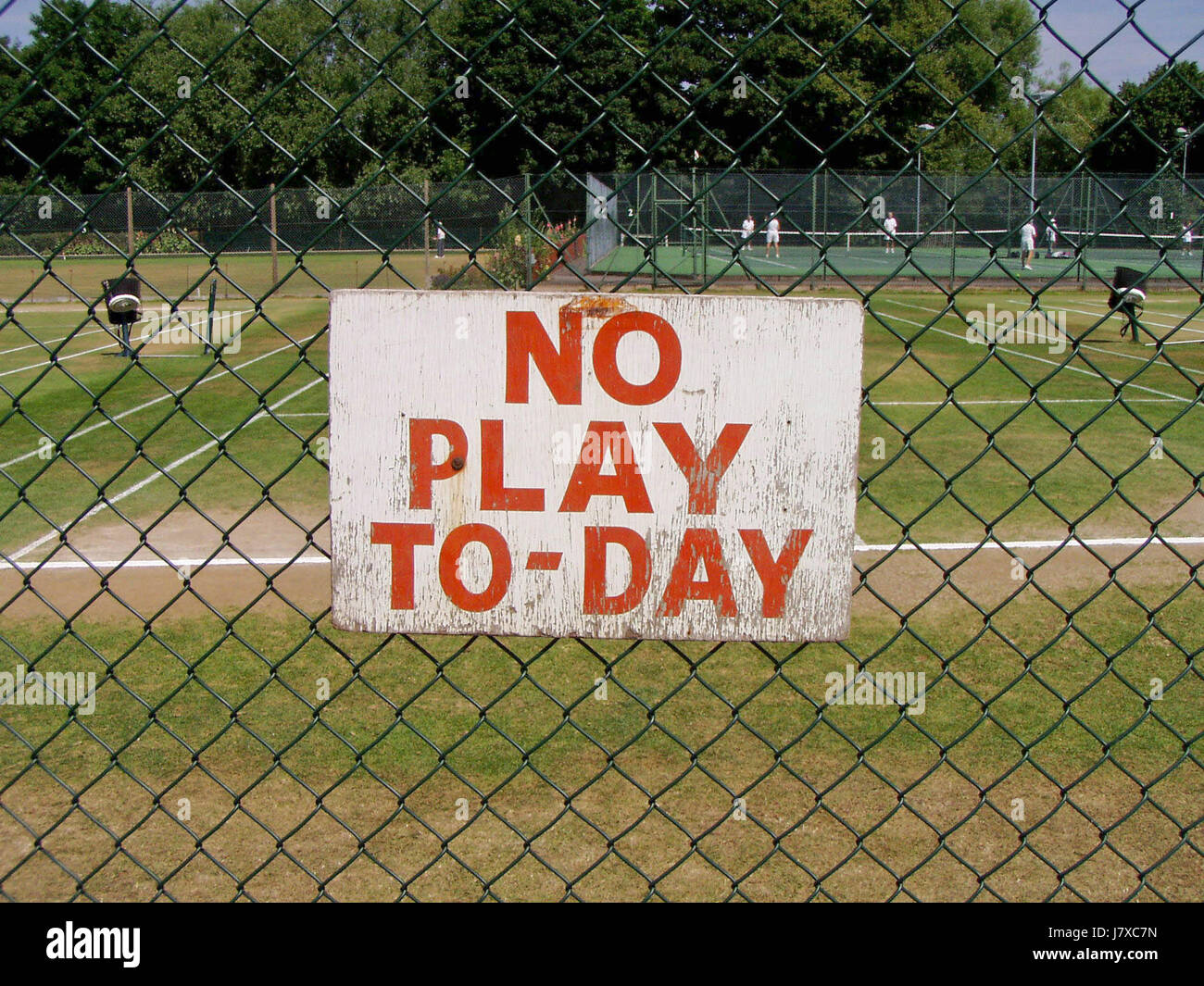 A 'no play today' sign on a fence at grass tennis courts at a club in Ealing, west London, England, UK in 2006. The hand-painted sign refers to 'TO-DAY' rather than the normal spelling of 'TODAY' Stock Photo