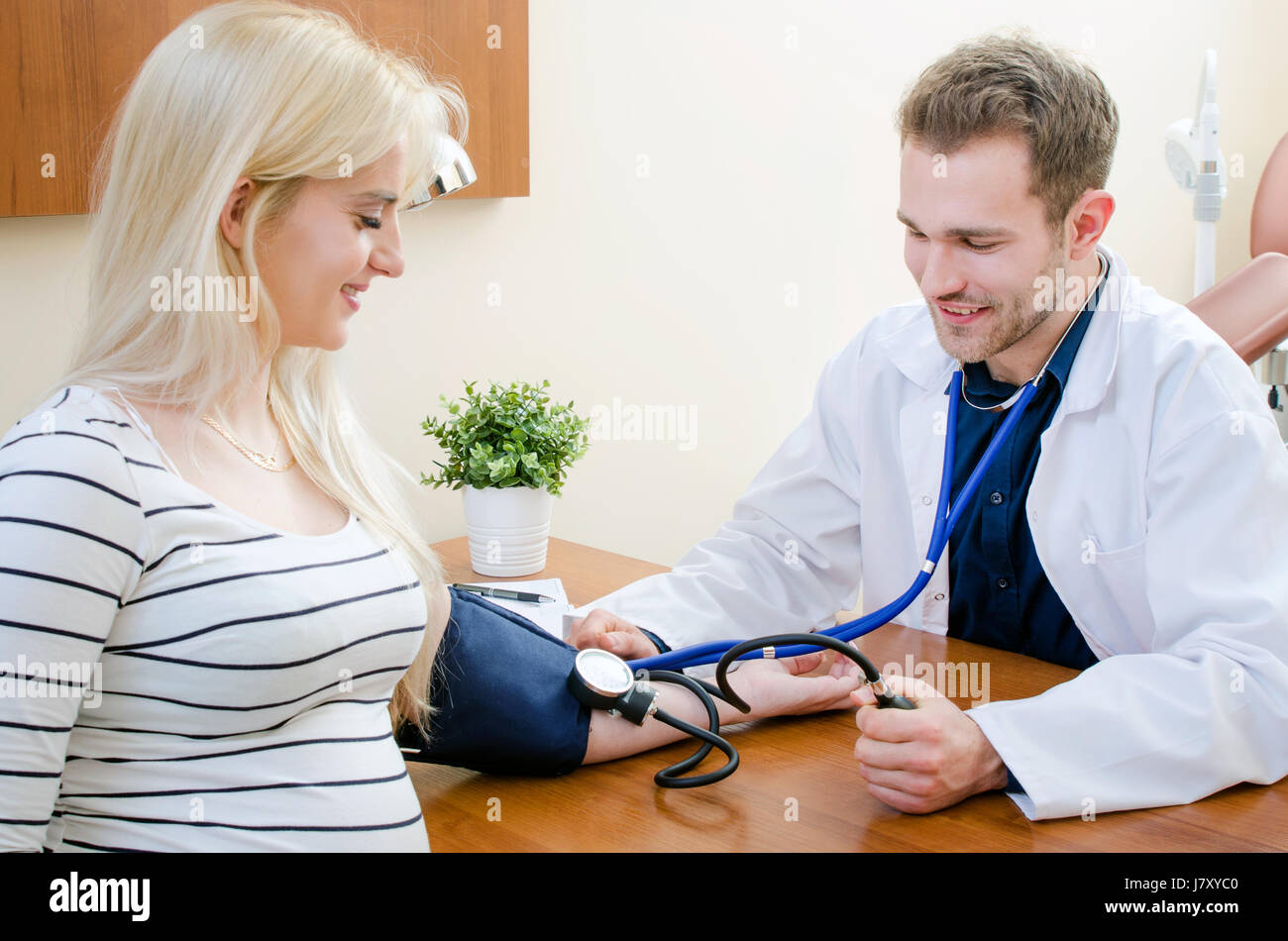 Young doctor checking blood pressure of female patient. pressure blood doctor patient medical heart sphygmomanometer measuring concept Stock Photo