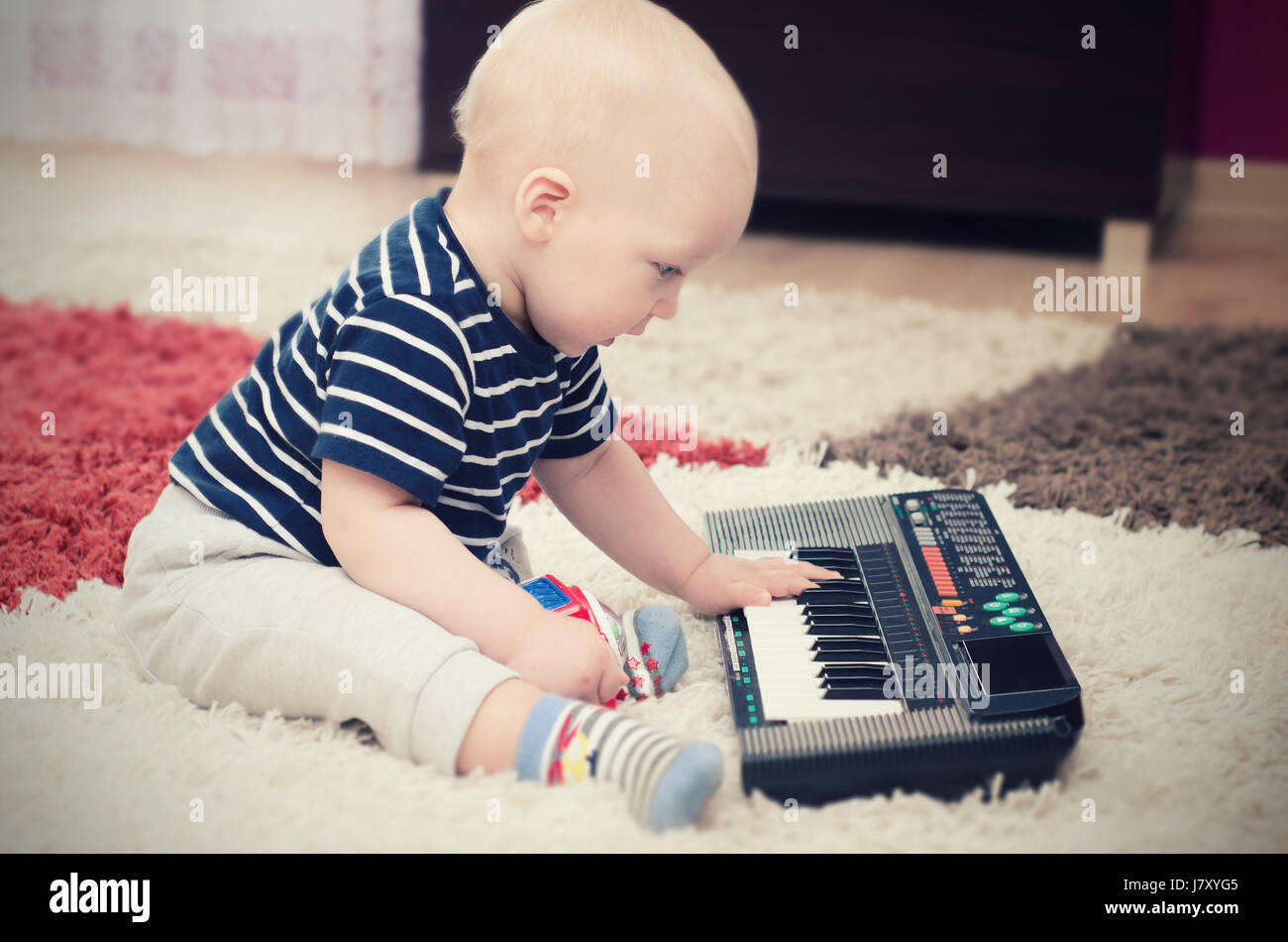 Little baby boy plays on keyboard toy. baby piano music playing child white cute little concept Stock Photo