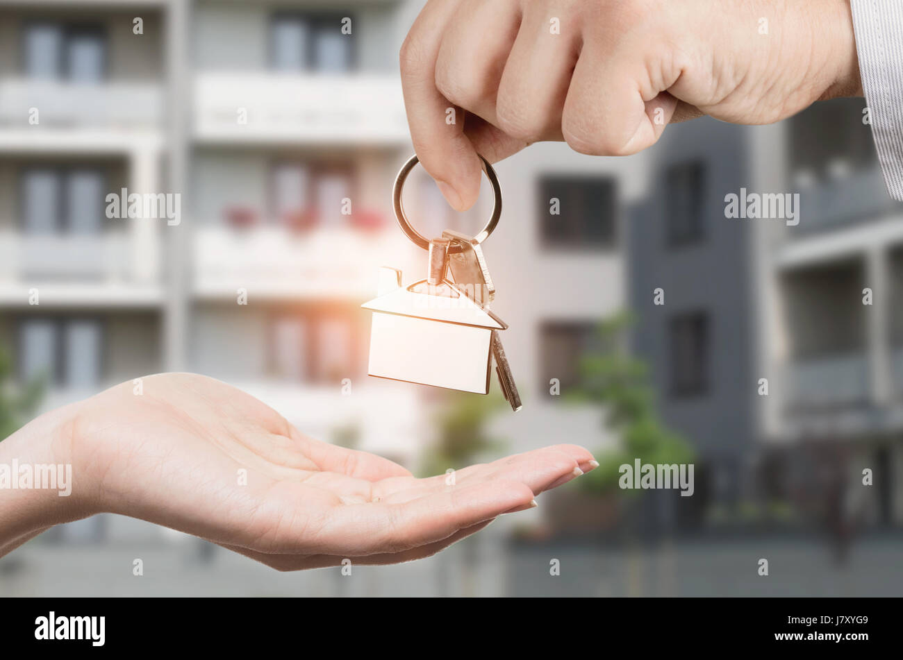 Man gives a woman the keys to a new home. Chrome pedant with house shape Stock Photo