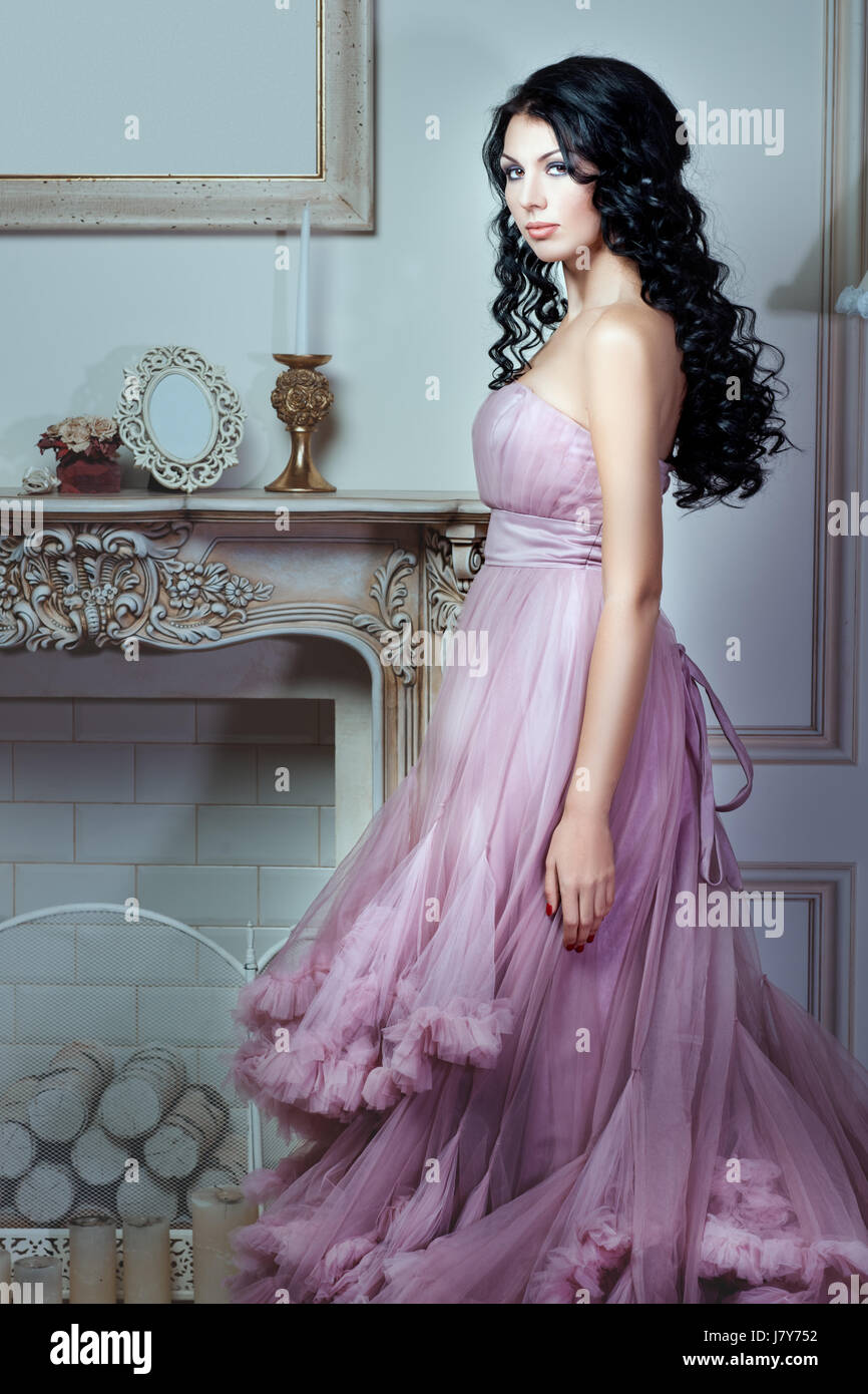 pink hair black dress Beautiful girl with pink hair with a black skull and an apple in her hands. Informal appearance. Tattoos on the hands. A piercing look. Black dress. Lying. Stock Photo