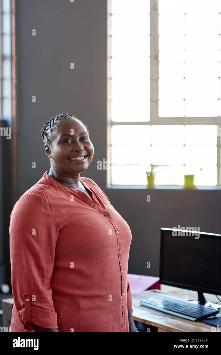 Smiling African businesswoman standing by her desk in an office Stock ...