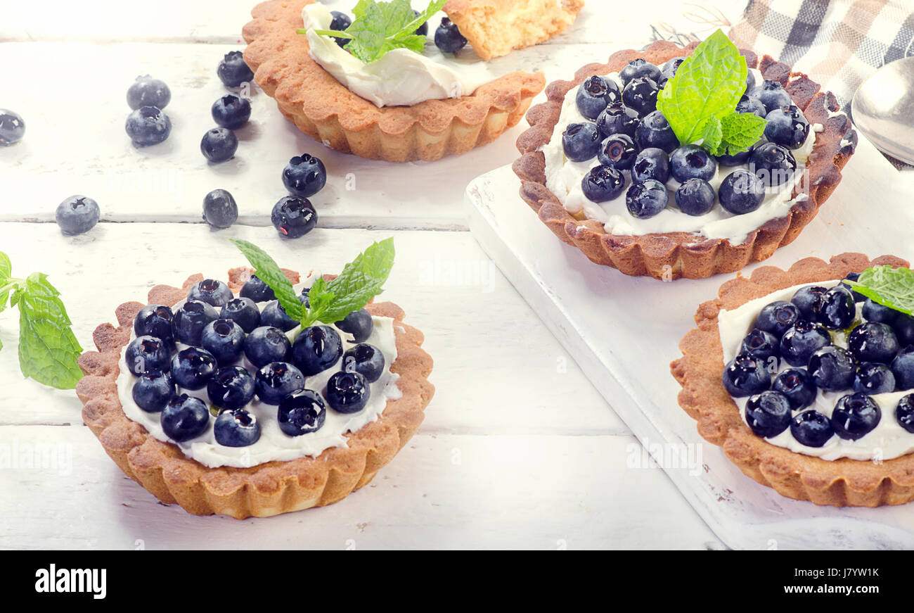 Sweet Blueberry tarts on a white wooden background. Stock Photo