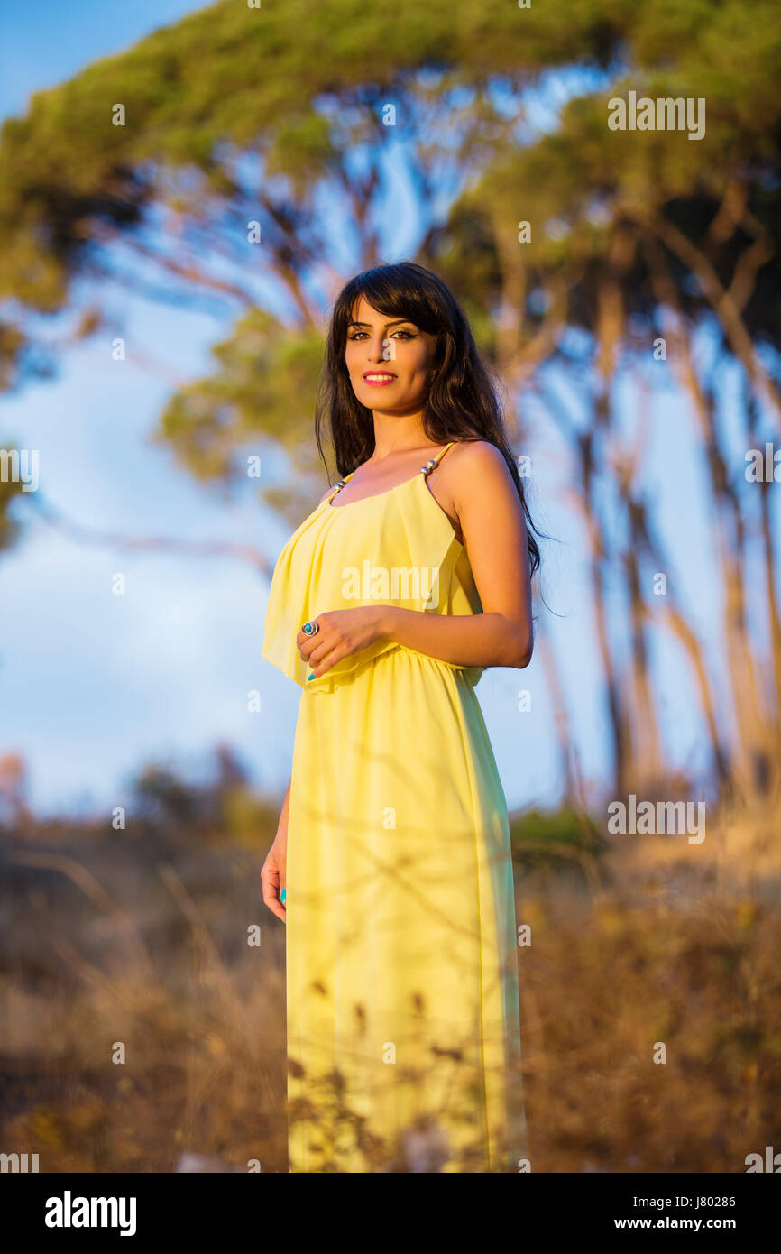 Happy young woman wearing a yellow summer dress standing outdoors ...