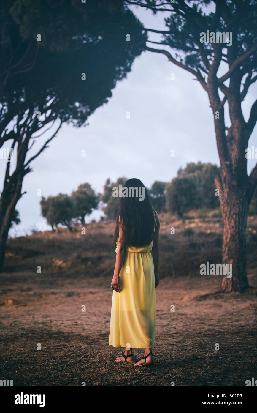 Rear view of a woman wearing a yellow summer dress walking away in
