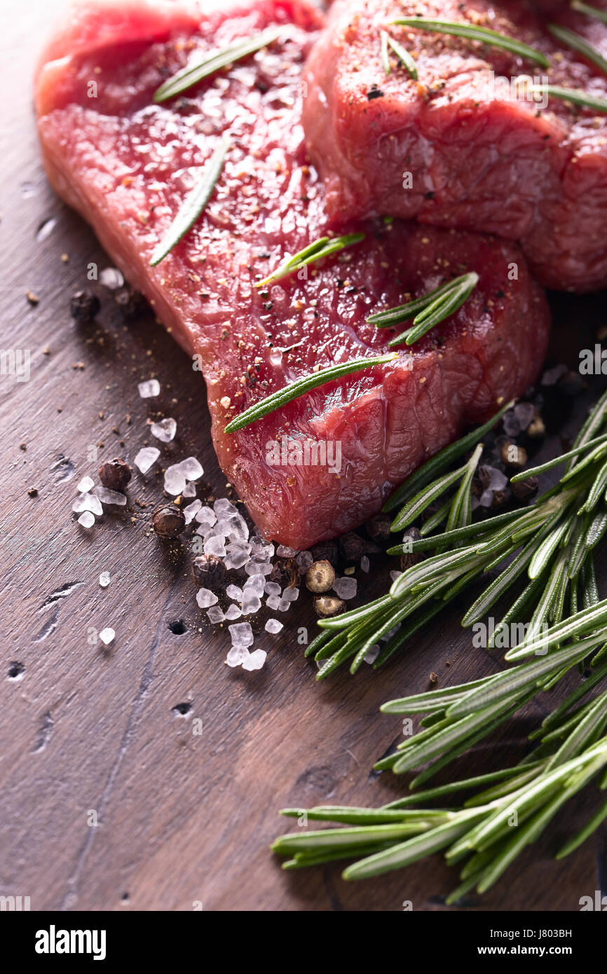 Beef steaks with rosemary , salt and pepper on a old wooden table Stock