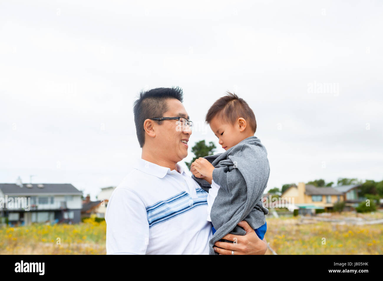 Chinese father holding son in park Stock Photo