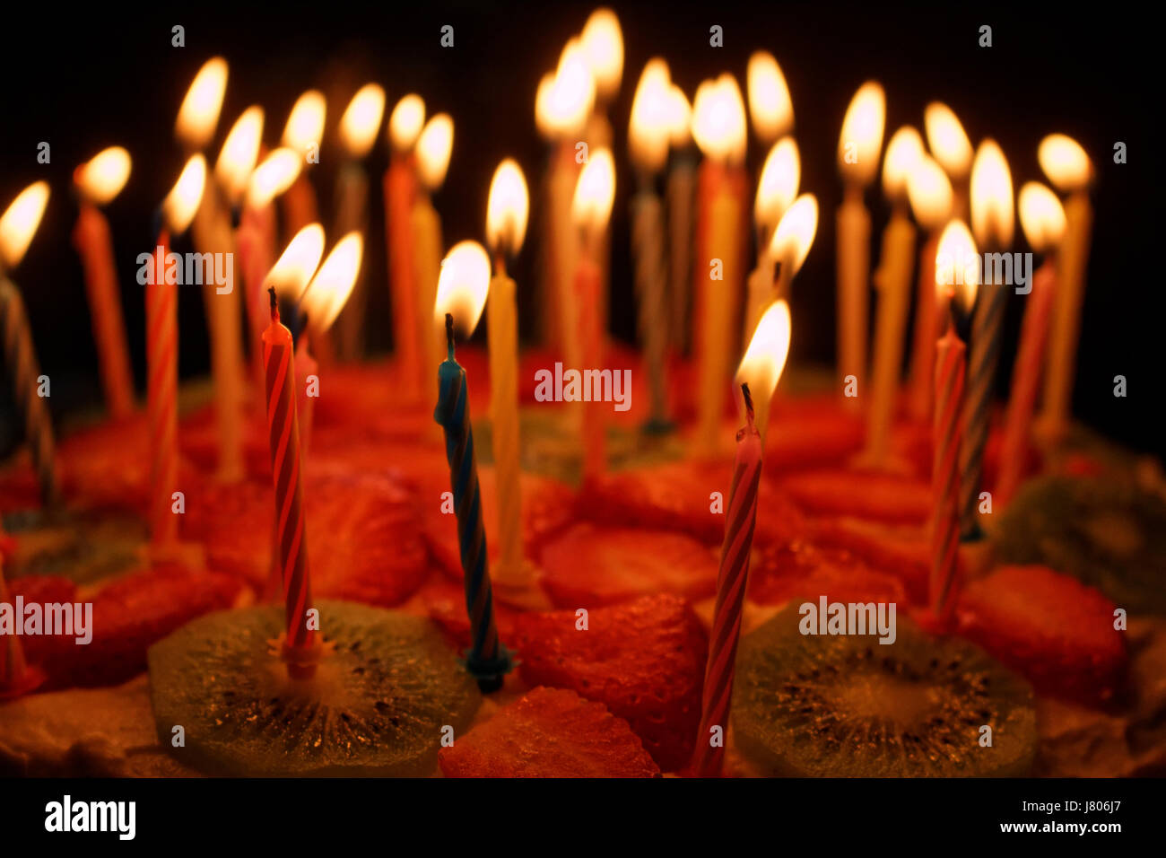 Birthday cake with burning candles on a dark background Stock Photo - Alamy