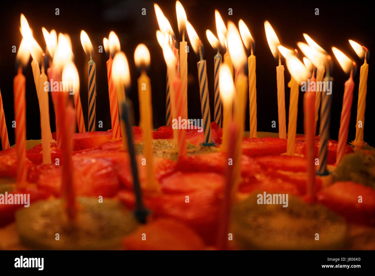 Birthday cake with burning candles on a dark background Stock Photo - Alamy