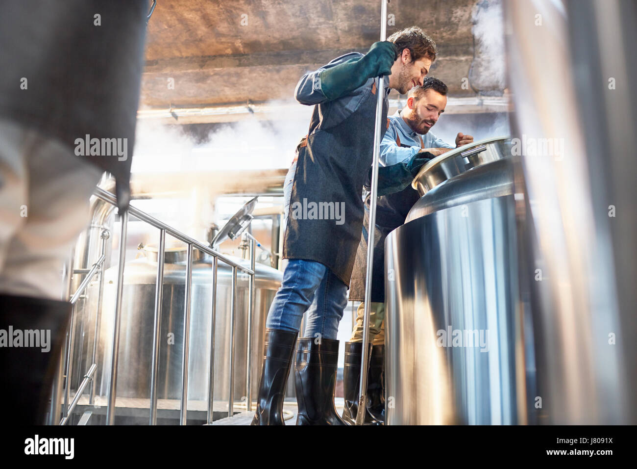Male brewers checking vat in brewery Stock Photo