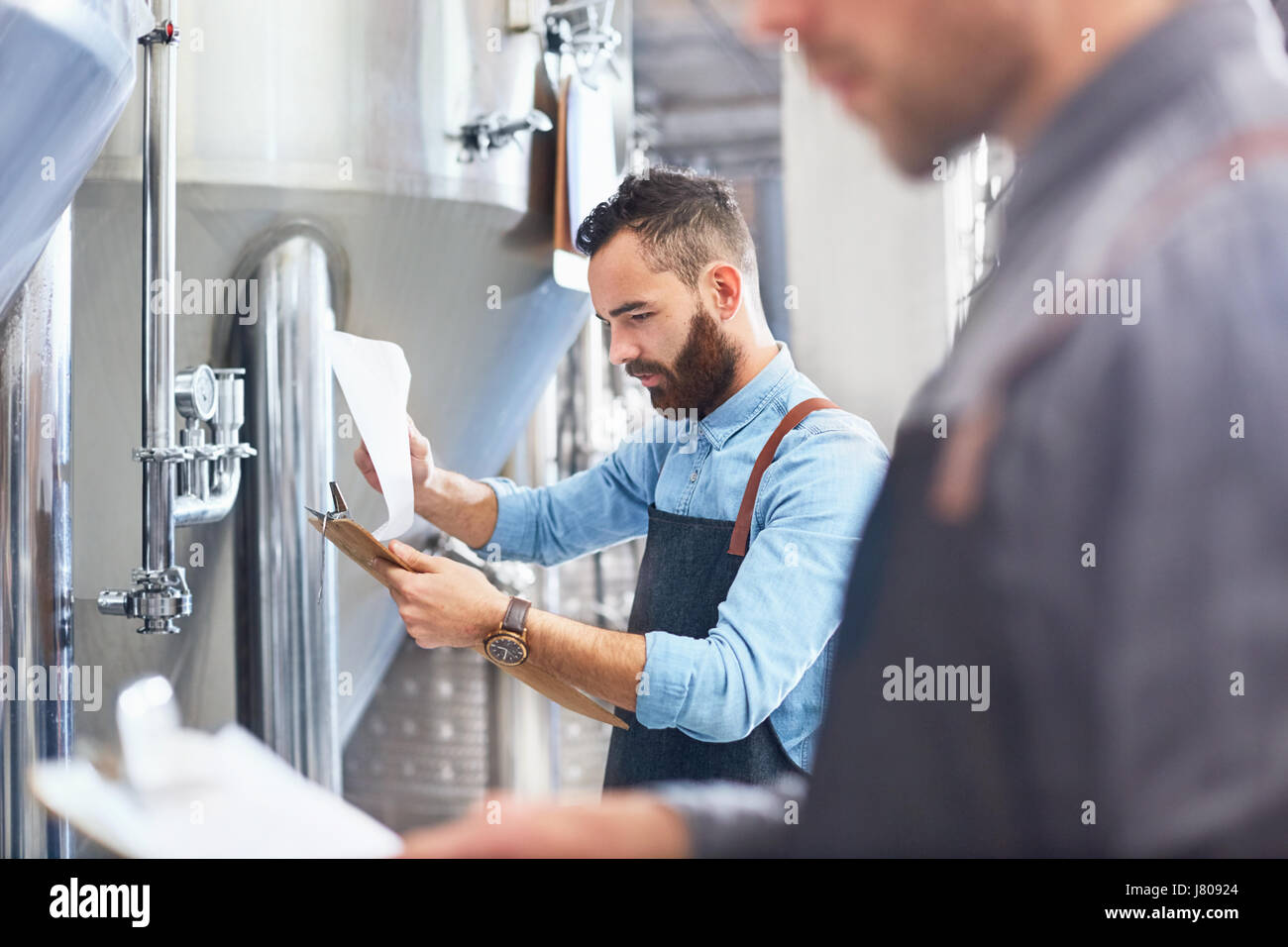 Male brewer with clipboard at vat in brewery Stock Photo
