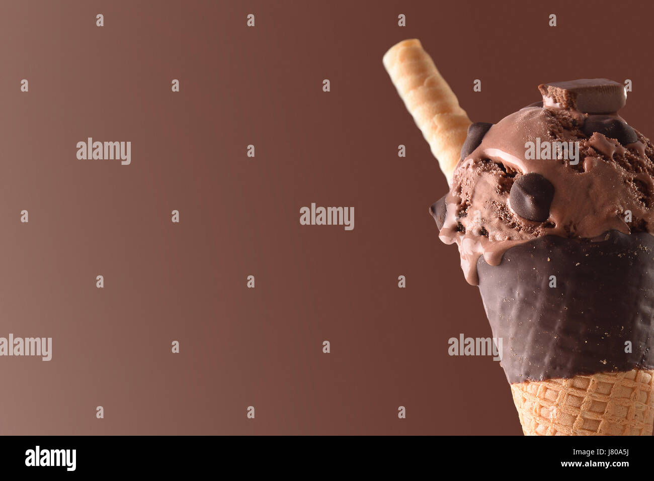 Ice cream cone flavored chocolate. Garnished with drops and squares of chocolate. With brown background. Horizontal composition. Stock Photo