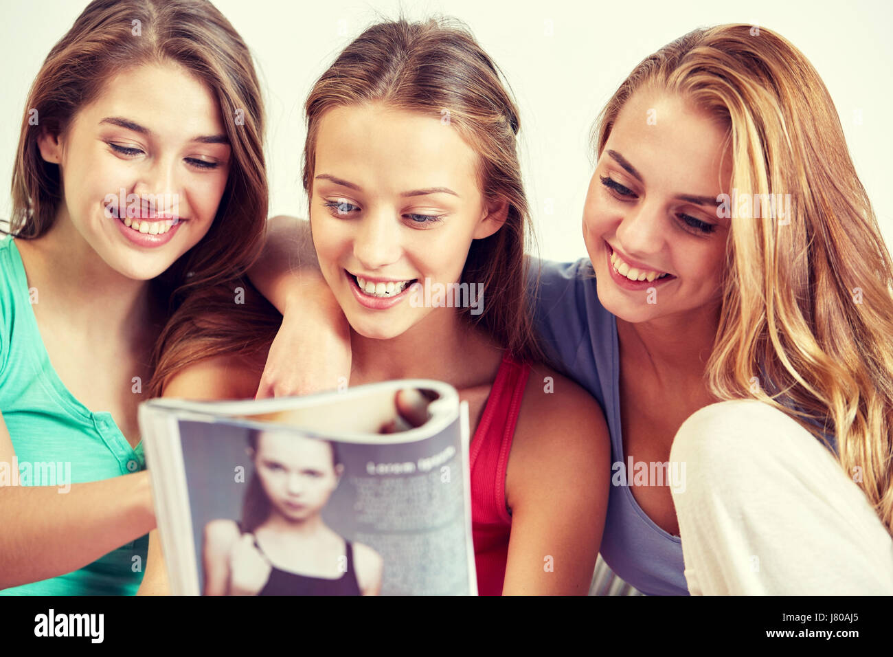 1980 1980s 2 TEENAGE GIRLS SISTERS SIT ON HEARTH READING MAGAZINE