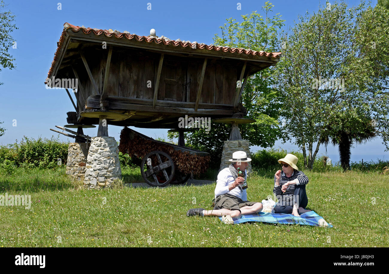 Couple picnic next to Horreo a traditional Asturias granary perched on cliffs overlooking the Atlantic at Cadavedo, Asturias, Spain. holiday holidays Stock Photo