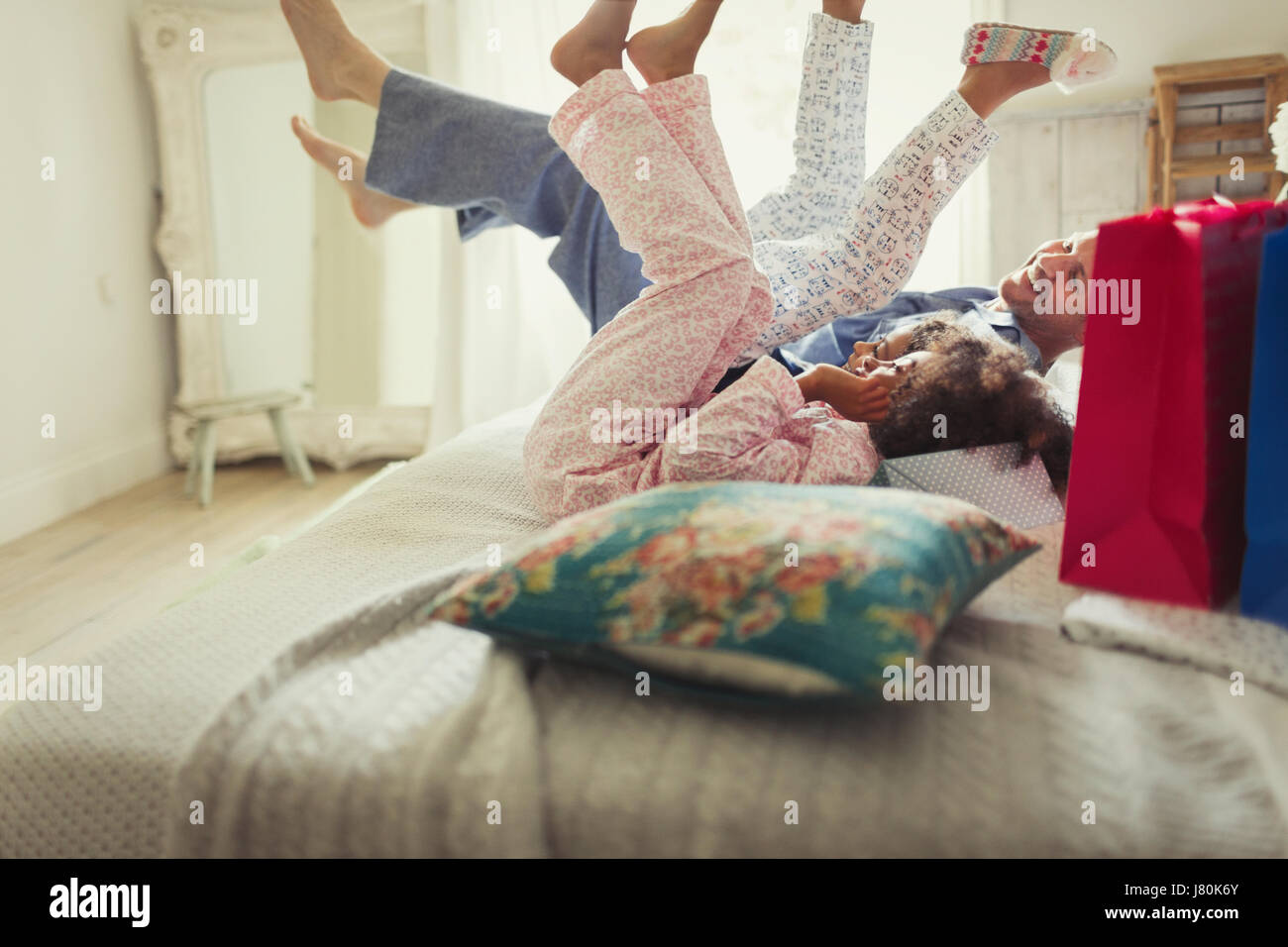 Father and daughters in pajamas kicking legs on bed Stock Photo