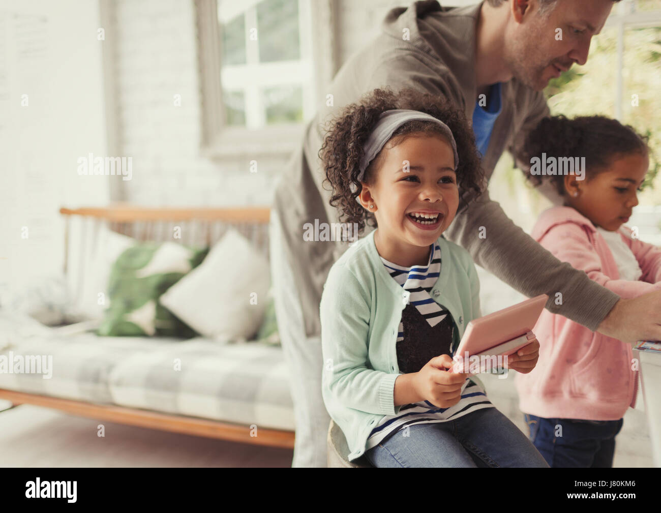 Laughing girl using digital tablet in living room Stock Photo