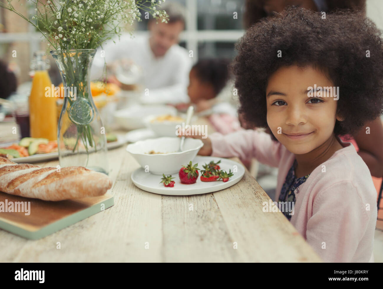 Portrait smiling girl eating strawberries at breakfast table Stock ...