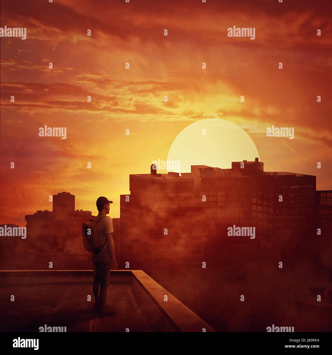 Young boy stay on the rooftop looking at the sunset. Mysterious place over the misty city Stock Photo