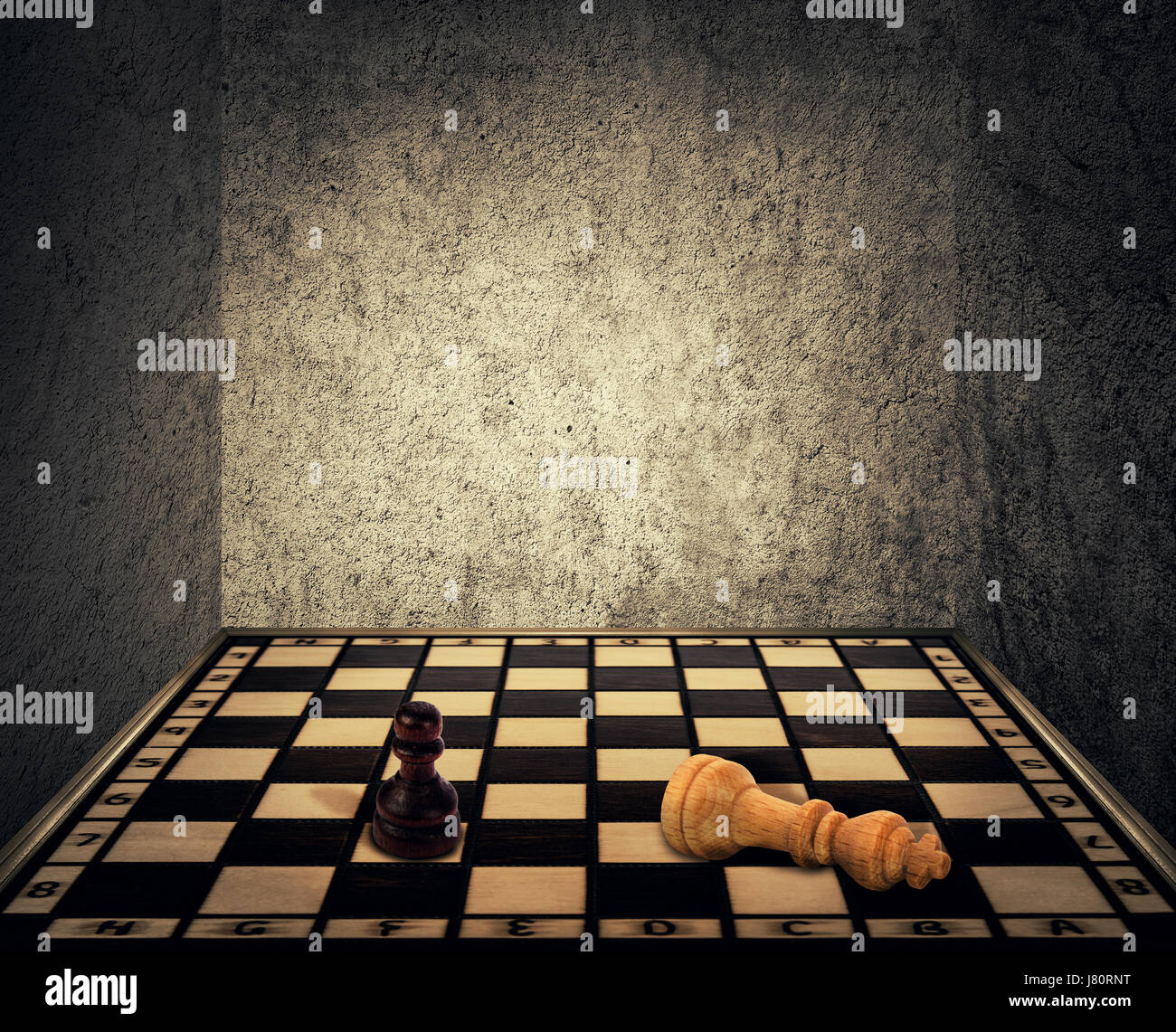 Magical room with a chess board floor surrounded by concrete walls as limitations and the king piece falling down beaten in front of the pawn figure.  Stock Photo