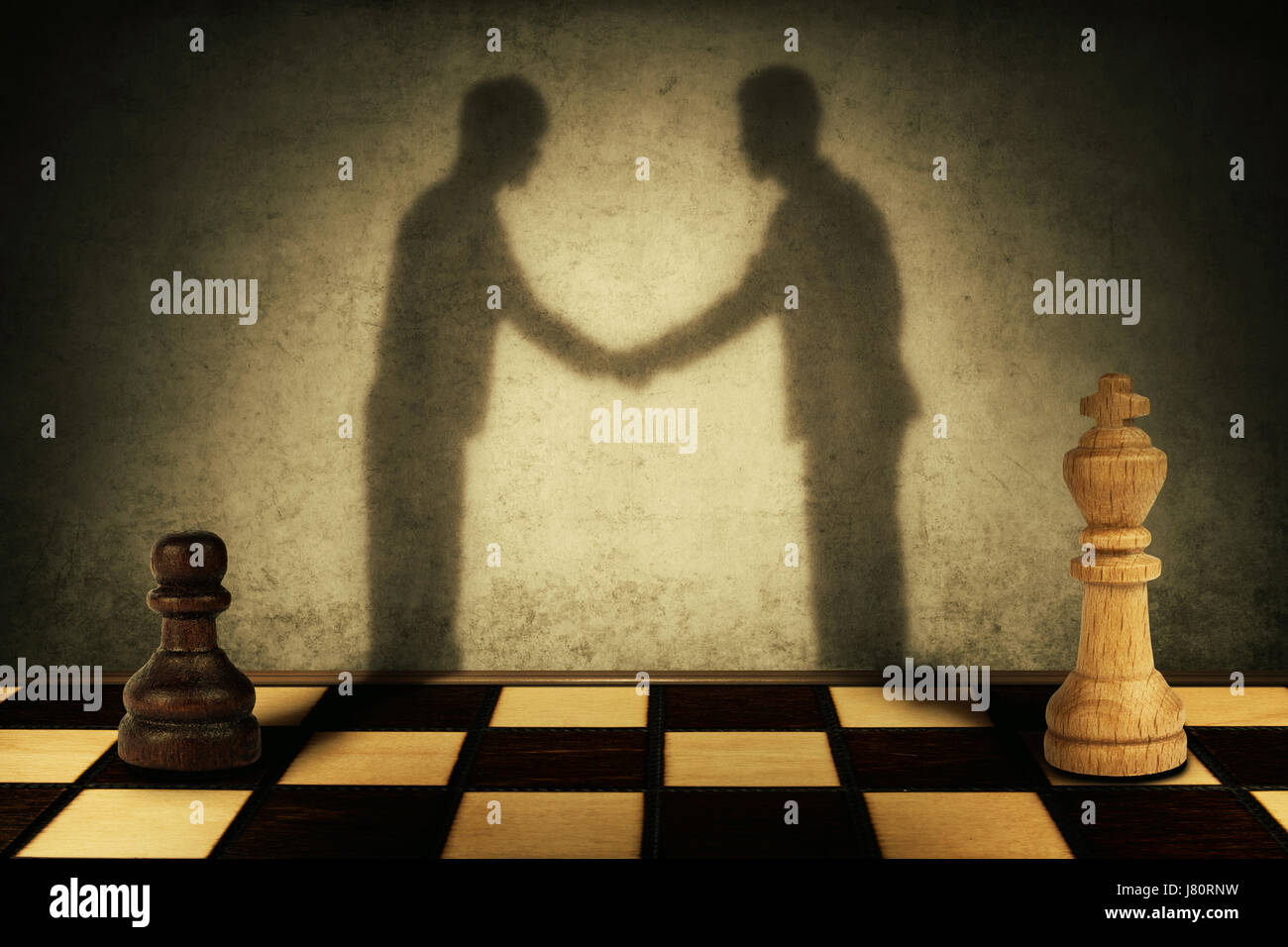 Chess pawn and king standing in front one another with their shadow transform into businessman giving handshake. Business hierarchy levels peace conce Stock Photo