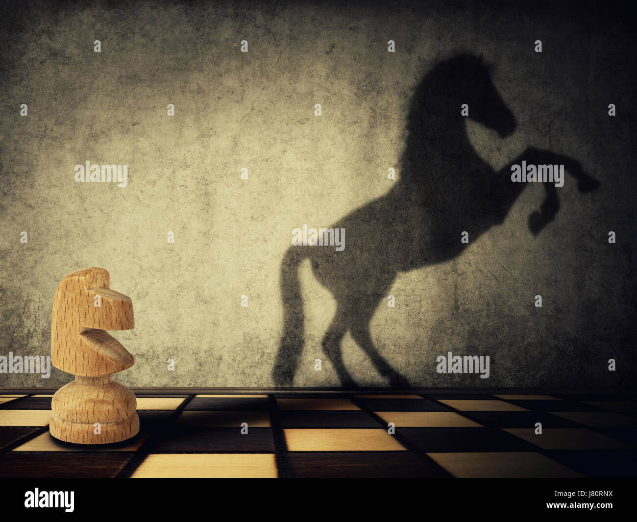 Magical transformation as a wooden knight chess piece casting a shadow of a wild horse on two legs on the wall. Symbol of business aspirations, freedo Stock Photo
