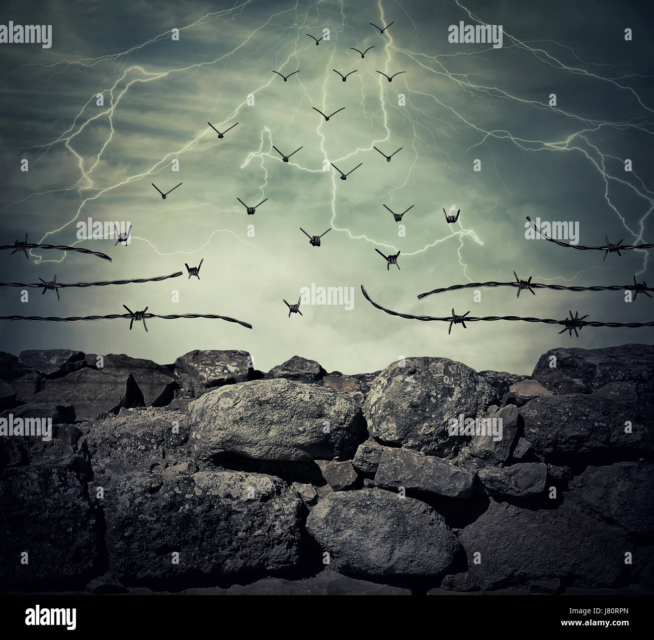 Stone wall fence of a prison with barbed metallic wire on top transform into flying birds over the lightning sky background. Freedom and success conce Stock Photo