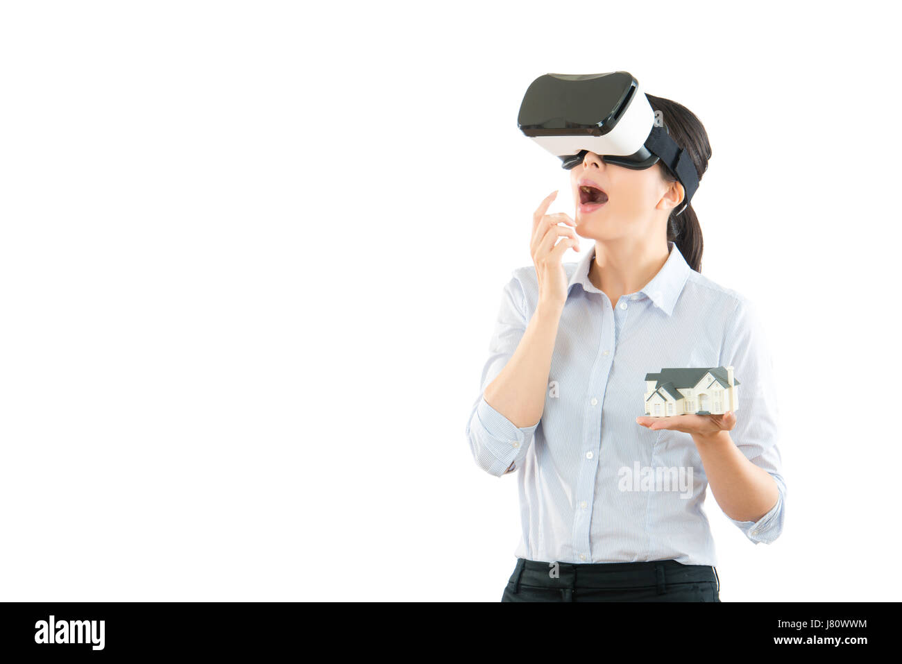 excited young office woman using a VR headset and experiencing virtual reality isolated on white background showing house design model and surprised o Stock Photo