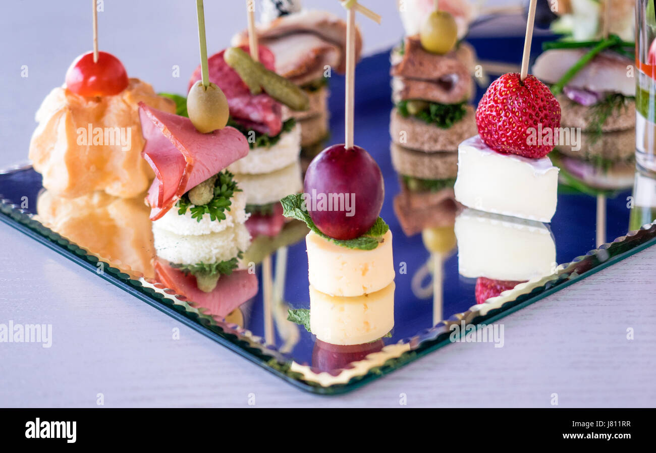 Set of different canapes and snacks served on a platter with a mirror