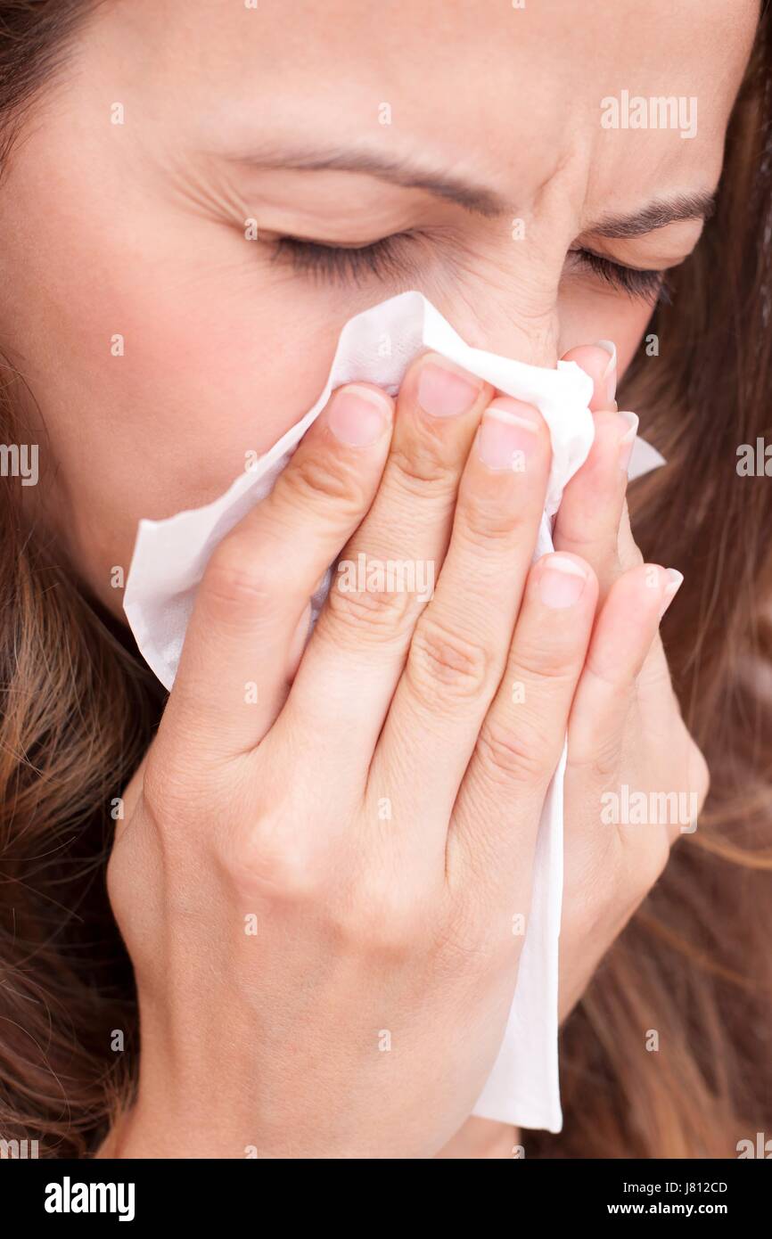 Woman blowing nose on tissue Stock Photo