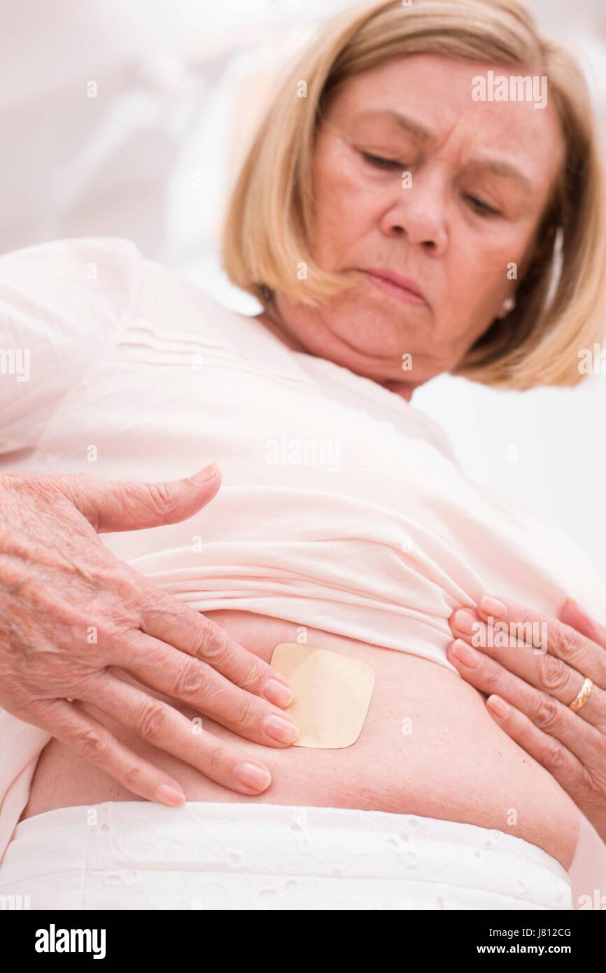 Woman applying hormone patch to tummy. Stock Photo