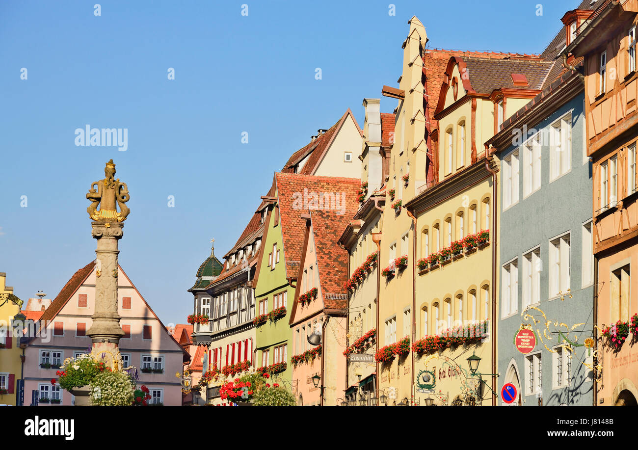 Germany, Bavaria, Rothenburg ob der Tauber, Colourful row of house patterns and fountain statue on Herrngasse off Marktplatz. Stock Photo
