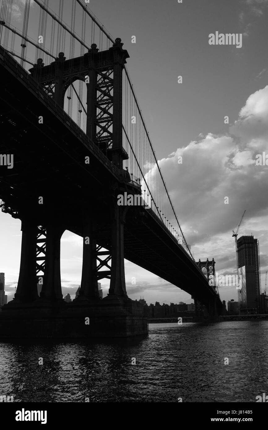 View across the East River with silhouettes of the supporting pier legs of the Manhattan Bridge from DUMBO in Brooklyn, New York. City landscape on a  Stock Photo