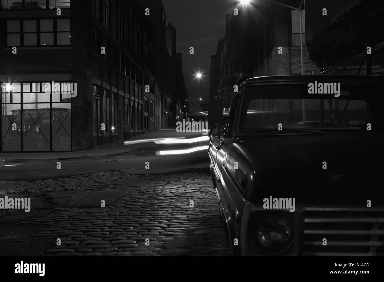 Night vanishing point view down Water Street in DUMBO, Brooklyn, long exposure background with retro look. Sodium street lights on and light trails fr Stock Photo