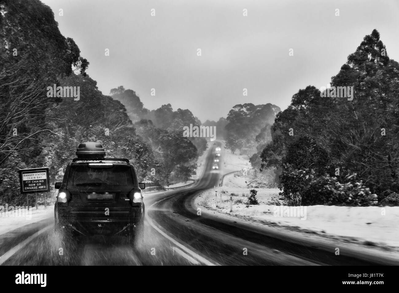 Slippery remote mountain road in Thredbo valley during snowfall and storm late at sunset. Popular skiing resort destination for australians in Snow mo Stock Photo