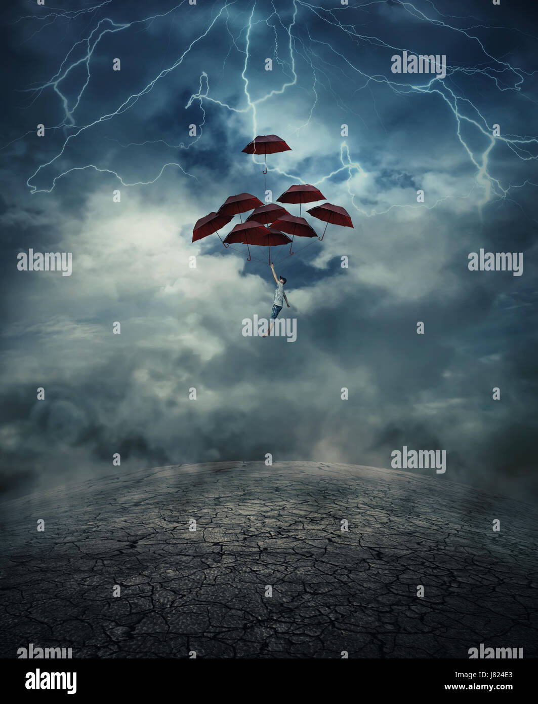 Young man with a lot of umbrellas as an air balloon rise up to the sky full of lightnings, above the cracked desert ground. Risk and success concept. Stock Photo