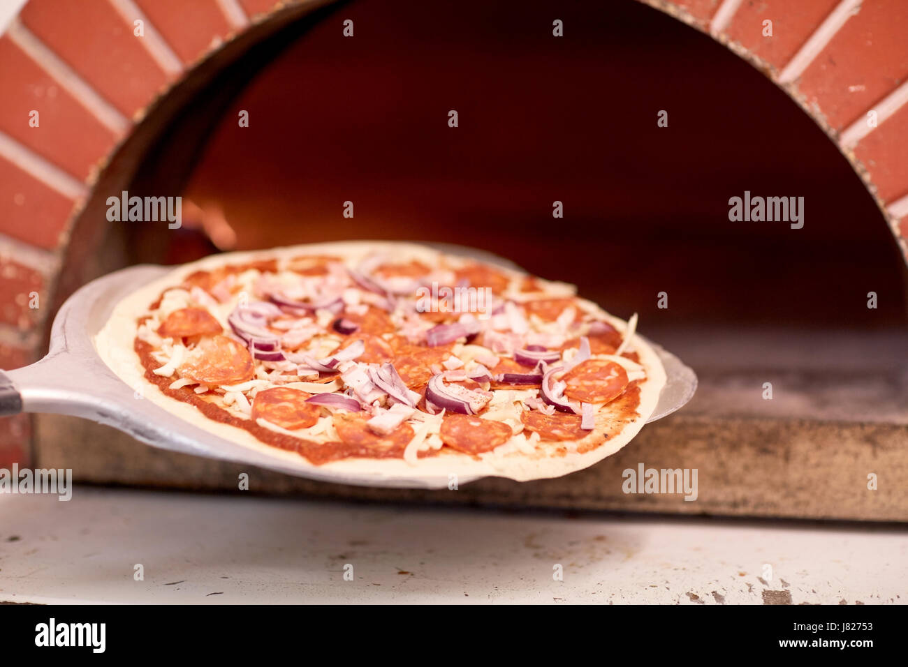 peel placing pizza into oven at pizzeria Stock Photo Alamy