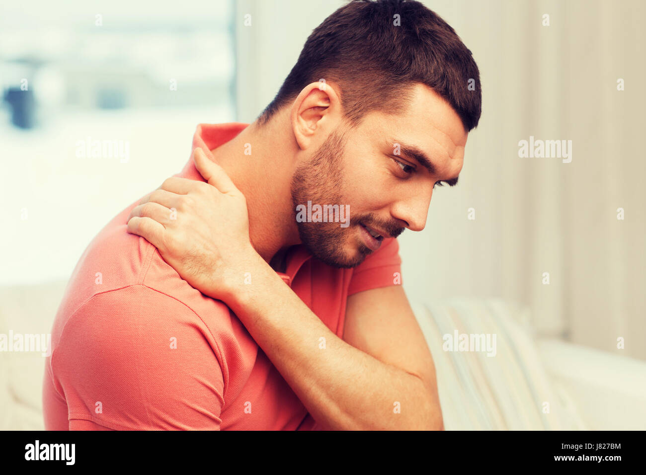 unhappy man suffering from neck pain at home Stock Photo - Alamy